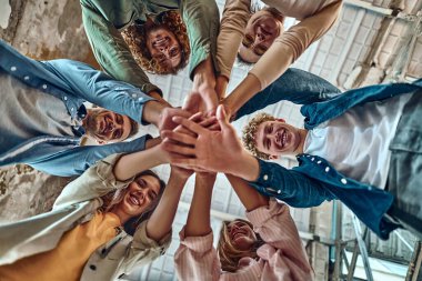 Bir grup insan ellerini birbirinin üstüne koyarak birliklerini gösteriyor. Arkadaşlık, mutluluk, eğlence, ortaklık ve takım konsepti. Alt görünüm.