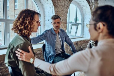 Yıkılmış bir genç adam ve arkadaşlarının grup terapisi sırasında onu destekledikleri yakın plan görüntüsü. Seçici odak