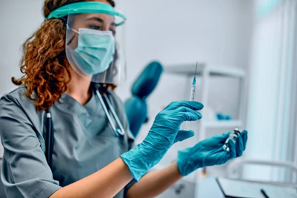 Koruyucu maskeli ve koruyucu tıbbi eldivenli bir kadın doktor kovid 19 aşısı ve şırınga tutuyor. Aşı ve sağlığın korunması ve korunması.