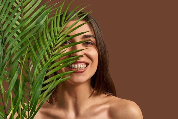 Portret Pięknej Kobiety Brązowym Tle Trzymającej Gałąź Palmy Uśmiechającej Się — Zdjęcie stockowe