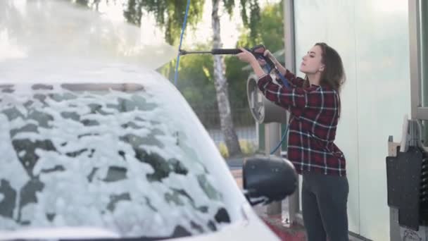 En kvinne som vasker bilen sin. – stockvideo