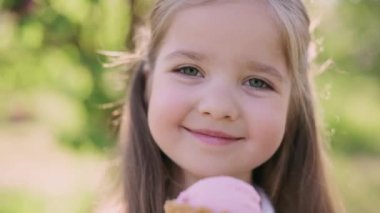 Dondurma yiyen ve gülümseyen kameraya bakan dört yaşında tatlı bir kız. Açık hava portresi..