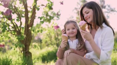 Anne ve kızı boş zamanlarını parkta geçirirler. Genç bir kadın ve dört yaşındaki kızı dondurma yiyorlar..