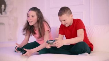 Çocuklar evde video oyunu oynarlar. Erkek ve kız aktif olarak oyunda yarışıyorlar..