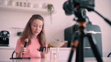 Blogger girl is recording tutorial video on applying makeup at home.
