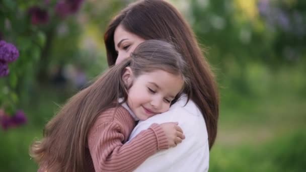 一位年轻的母亲把一个可爱的小女儿抱在一棵开花的树上 一个4岁的女孩在一位慈爱的母亲怀里的画像 — 图库视频影像