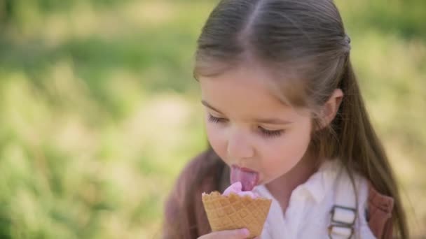 귀여운 소녀가 아이스크림을 먹으면서 카메라를 있습니다 클로즈업 — 비디오