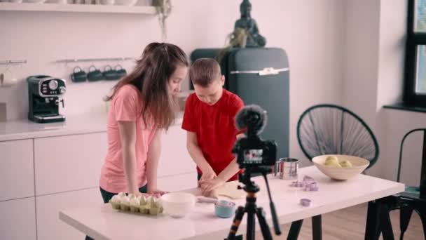 男孩和女孩在家里记录烹饪博客 那男孩用滚针把面团铺成饼干 Steadicam中枪 — 图库视频影像