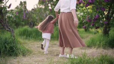 Anne ve kızı eğleniyor. Parkta annesinin etrafında koşan dört yaşında bir kız. Yavaş çekim.