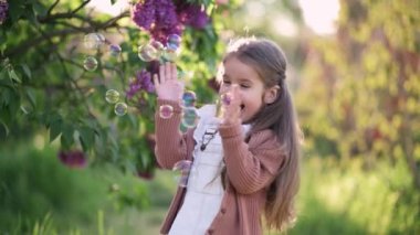 Dört yaşında tatlı bir kız, elleriyle parkta sabun köpüğü yakalarken eğleniyor. Mutlu tasasız çocukluk.