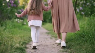 Anne ve kızı çimlerin üzerinde yürüyorlar, dikiz aynasından. Aile boş zamanlarını parkta geçirir..