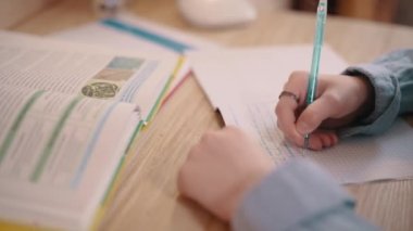 Ödev yapan bir kız. Kız odasındaki masada deftere yazıyor. Kaydırıcı atışı, ellerinizi kapatın..