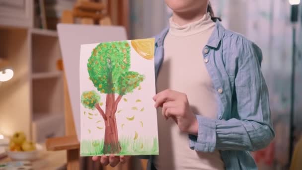 十代の女の子は彼女の手に彼女が描いた木の絵を保持しています — ストック動画