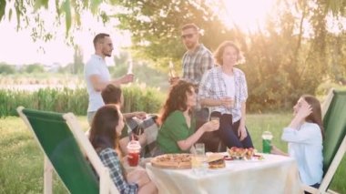Bir grup arkadaş dışarıda birlikte dinleniyorlar. Genç, neşeli insanlar konuşuyor ve gülüyor..