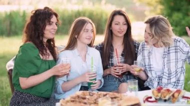 Kız arkadaşlar eğleniyor. Dört neşeli genç kadın duygusal olarak dışarıda konuşuyor ve gülüyor..