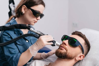 Sakal çevresindeki lazer tüy dökülmesi. Epilasyon ustası lazerli bir adamın boynunu tedavi eder..