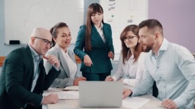 İş adamlarından oluşan bir ekip ofiste projeyi tartışıyor. Takım bir masaya oturur ve bir dizüstü bilgisayara bakar..