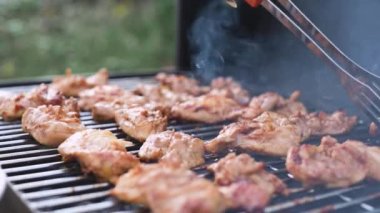 The meat is grilled. The cook flips a fried chicken fillet with tongs. Close-up.