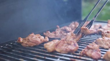 The meat is grilled. The cook flips a fried chicken fillet with tongs. Close-up.