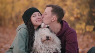 Köpekle oynayan bir çift. Genç mutlu çift, düşen yaprakların üzerinde otururken evcil hayvanlarını okşuyor. Macar çoban köpeği Buli doğada ürer..