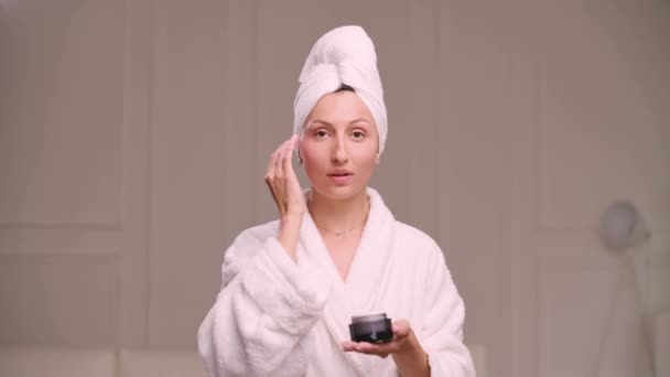 Young Attractive Woman Bathrobe Applies Cream Her Face Bathroom Skin — стоковое видео