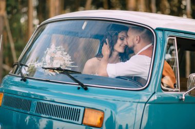 Boho tarzı yeni evliler klasik bir arabada sarılıyorlar..