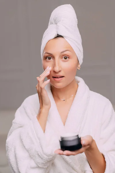 Young Attractive Woman Bathrobe Applies Cream Her Face Bathroom Close — Stock Photo, Image