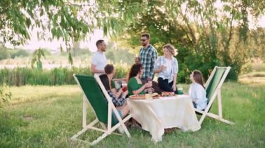 Bir grup arkadaş dışarıda birlikte dinleniyorlar. Genç neşeli insanlar kadehleri tokuşturup gülüyor..