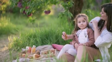 Anne ve kızı piknikte. Annem küçük kızına bir donatla davranır..