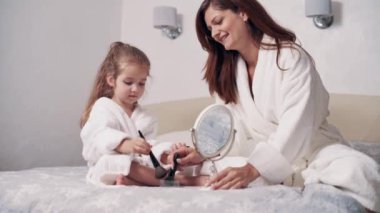 Sevimli anaokulu kızı ve annesi evde birbirlerine makyaj yapıyorlar..