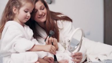 Sevimli anaokulu kızı ve annesi evde birlikte makyaj yapıyorlar. Kapat..