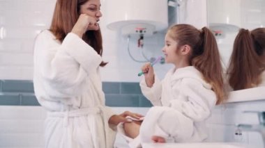 Genç bir anne ve dört yaşındaki kızı dişlerini banyoda fırçalarlar..