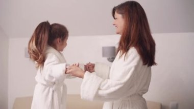 Anne ve kızı evde eğleniyorlar. Anaokulundan bir kız yatağa atlıyor..