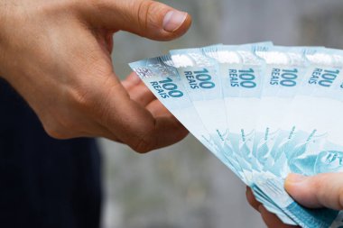 Yüz Reais banknotundan oluşan bir deste elden ele geçti. 