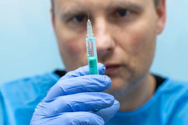 Elinde kullanıma hazır bir şırınga tutan bir sağlık görevlisi..