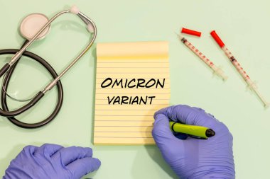 Omicron Varyant, bir virolog tarafından el yazısıyla yazılmış bir not, pastel yeşil bir masadaki tıbbi aksesuarlar. 