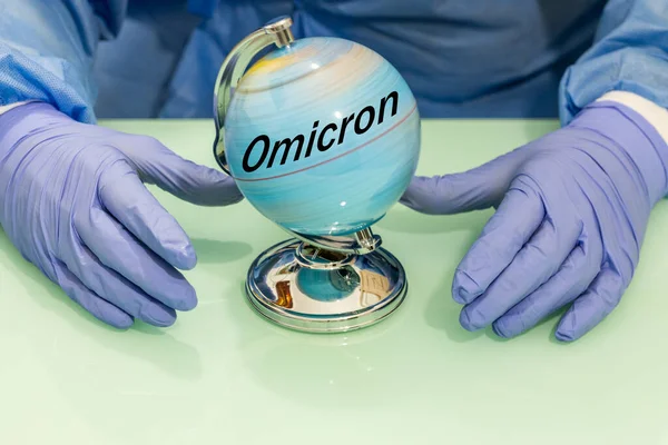 A fast spinning globe with the word Omicron on it. Doctor\'s hands in rubber gloves, The concept of the instant spread of a new variant of the coronavirus in the world