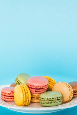 Mavi arka planda renkli badem kurabiyeleri. Lezzetli Fransız bademli tatlı kurabiyeleri. Metin için yer, dikey bileşim 