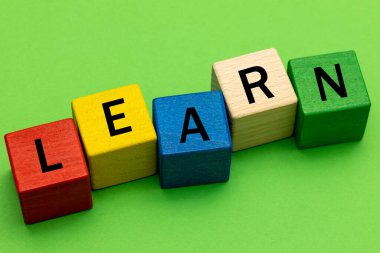 The inscription Learn made of colored blocks lying on a green background, The concept of development and learning for both children and adults, Horizontal photo, close-up 