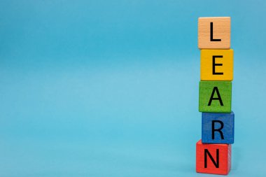 The inscription Learn composed of colored blocks arranged vertically on a blue background, Creative empty space, Concept of development and learning for children and adults, Horizontal photo 