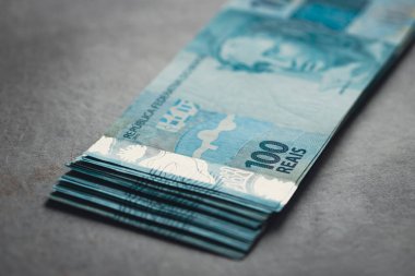 Bir tomar Brezilya parası, büyük miktarda 100 reais banknot, gri arka plan 