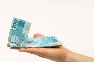 Brezilya parası uzanmış bir elde yatıyor, beyaz üzerine izole edilmiş, 100 Reais banknot, metin, ekonomi ve iş konsepti için alan 