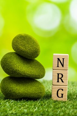 Yeşil enerji, ahşap bloklar, yeşil arka plan, kavram, sürdürülebilir gelişim, CO2 emisyonları olmadan enerji elde eden yosunlu taşların yanında 