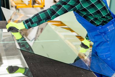 Camcı, cam bir bölmeyi özel bir masaya yerleştirir ve cam fabrikasında çalışır. 