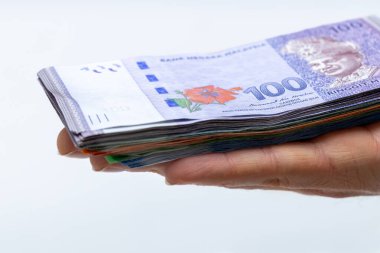 Malezyalı ringitler uzanmış bir elin üzerinde, bir sürü banknot, yüksek değer, hafif geçmiş, ekonomi ve iş konsepti 