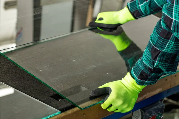 The glazier puts the glass on the cutting table in the glass factory, Trimming glass panels