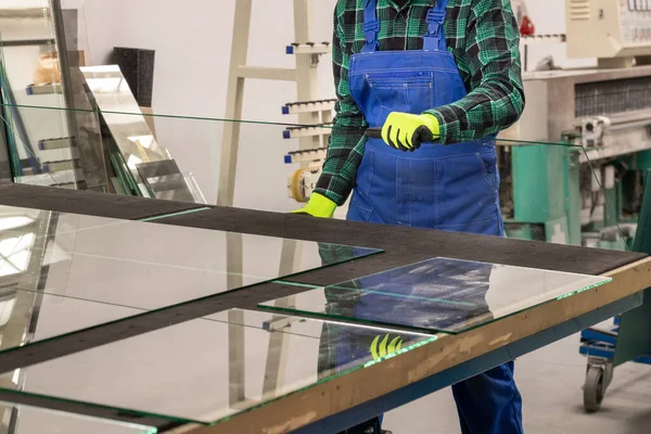 The glazier places the glass pane on a specialized cutting table, Glass factory