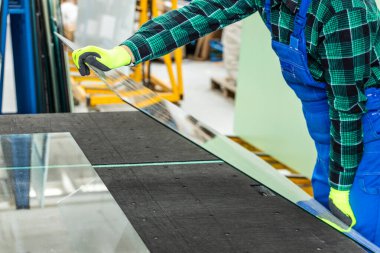 Camcı, cam bir bölmeyi özel bir masaya yerleştirir ve cam fabrikasında çalışır. 