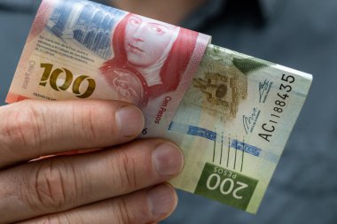 100 ve 200 Meksika pezosu ellerinde, finans sektörü konsepti, büyük banknotlar, kapatın.