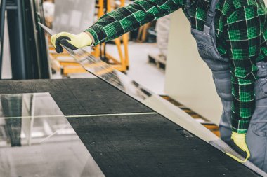 Camcı, cam bir bölmeyi özel bir masaya yerleştirir ve cam fabrikasında çalışır. 